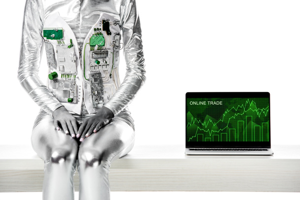 cropped image of robot sitting on table near laptop with online trade appliance isolated on white, future technology concept - Valokuva, kuva