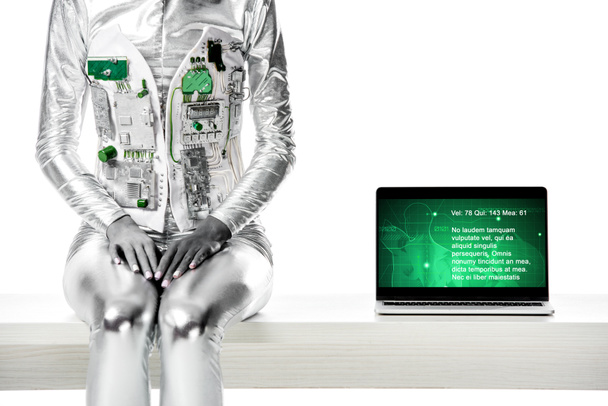 cropped image of robot sitting on table near laptop with medical appliance isolated on white, future technology concept - Valokuva, kuva