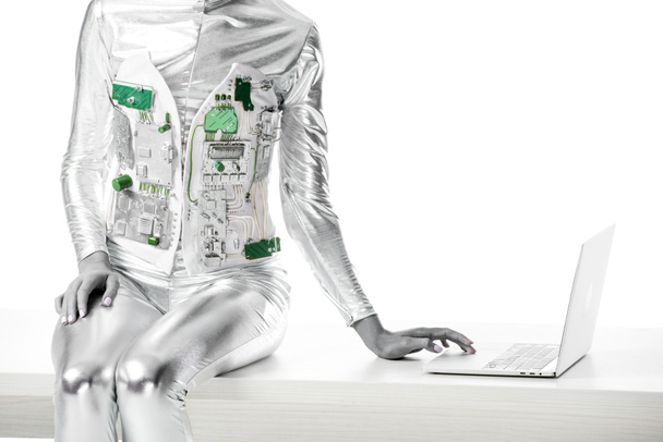 cropped image of robot sitting on table and using laptop isolated on white, future technology concept - Фото, зображення