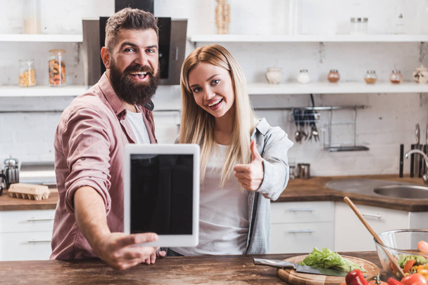 bearded man holding digital tablet with blank screen while woman showing thumbs up - Foto, immagini