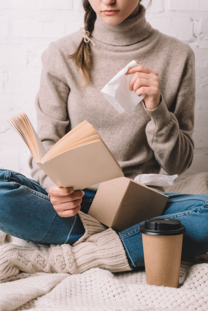 cropped shot of woman holding paper tissue and reading book - Foto, imagen