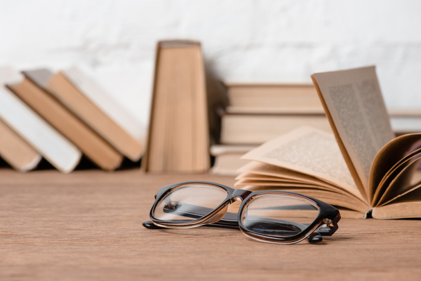close-up view of eyeglasses and books on wooden table - Фото, изображение