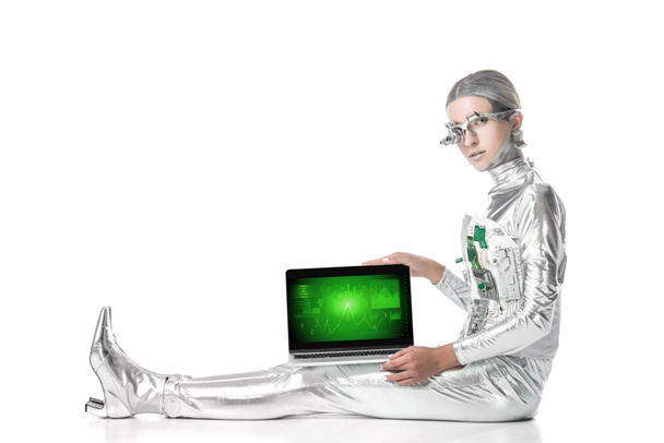 Zilveren robot zitten en toont laptop met zakelijke toestel geïsoleerd op wit, toekomstige technologie concept - Foto, afbeelding
