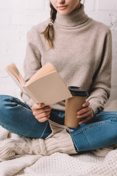 cropped shot of girl holding paper cup and reading book - Zdjęcie, obraz