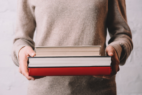 mid section of young woman holding books - Fotoğraf, Görsel