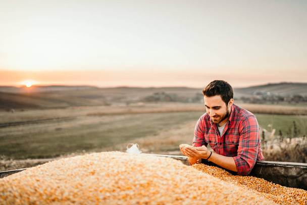 Portrait of harvester at sunset enjoying his harvest in tractor trailer - Fotografie, Obrázek