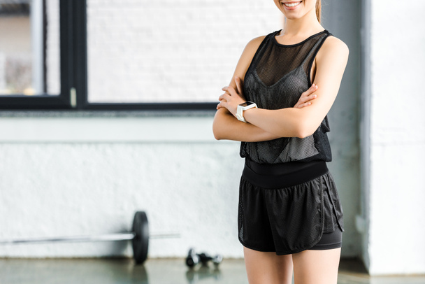 Ausgeschnittene Ansicht einer lächelnden Sportlerin in Schwarz im Fitnessstudio - Foto, Bild