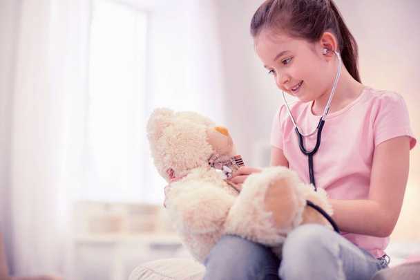 Cute preschool girl feeling entertained while playing with teddy bear - Foto, imagen