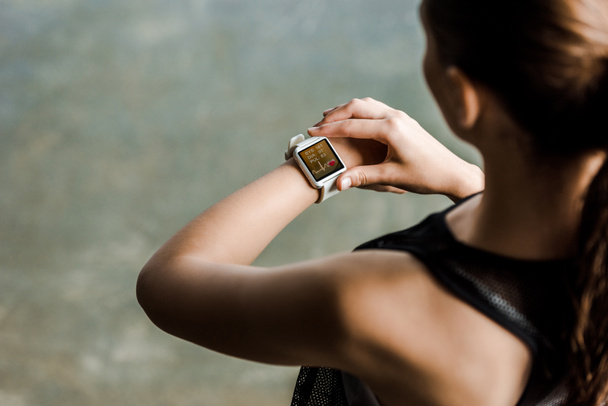 vista recortada de la deportista mirando el reloj inteligente deportivo que muestra el ritmo cardíaco en el gimnasio
 - Foto, Imagen