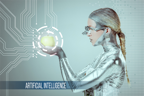 Widok z boku cyborga gospodarstwa i zbadanie zielone jabłuszko z danych cyfrowych na białym tle na szary z napisem "sztuczna inteligencja" - Zdjęcie, obraz