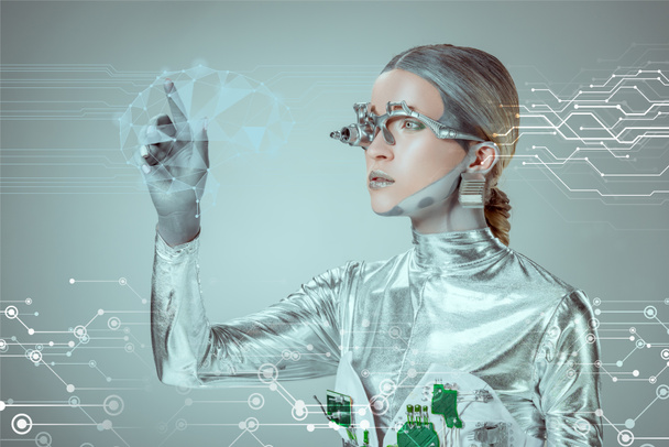 futuristische zilveren cyborg gebaren met hand en kijken naar digitale gegevens geïsoleerd op grijs, toekomstige technologie concept   - Foto, afbeelding