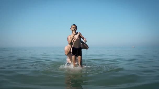 Dad throws his son out of the water playing with him on the beach, SLOW MOTION - Záběry, video