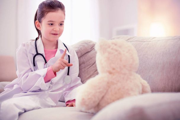 niedliches kleines Mädchen sitzt allein zu Hause und spielt mit ihrem Teddybär - Foto, Bild