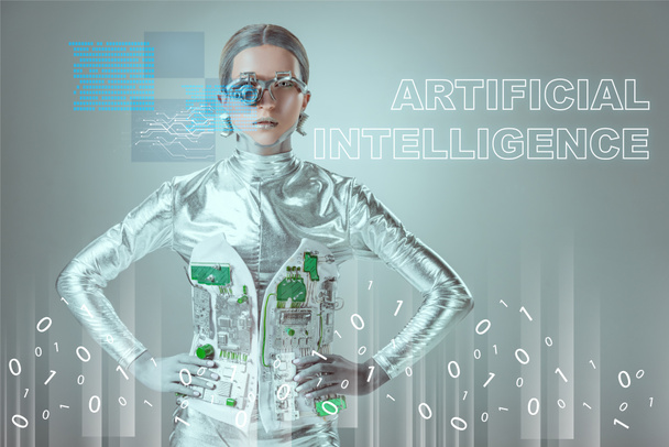 futuristic silver cyborg standing with hands on waist and looking at camera on grey with "artificial intelligence" lettering and digital data - Foto, Bild