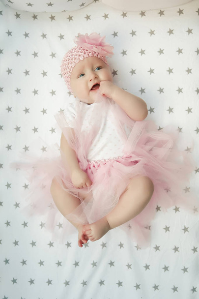 Aranyos baba arcképe bolyhos rózsaszín szoknyában, világos háttérrel. Kicsi szerelem. - Fotó, kép