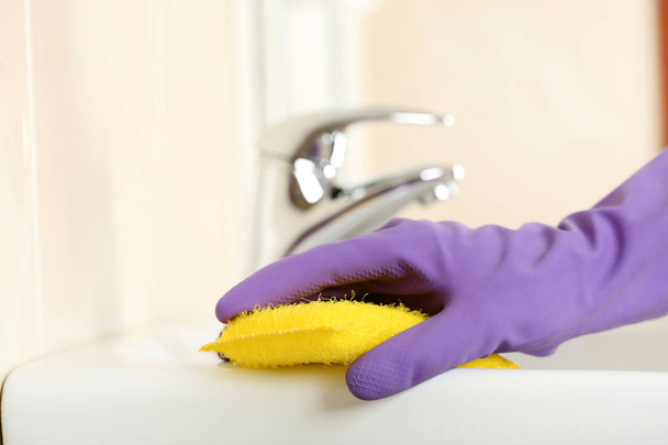 Hand in glove cleaning water tap in bathroom - Zdjęcie, obraz