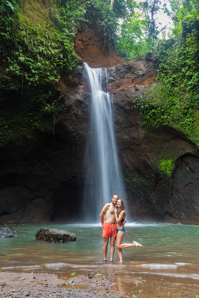 couple looking at the gorgeous waterfall in Bali - Фото, изображение