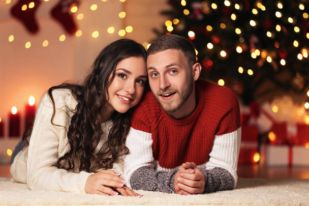 Young couple lying at home near christmas tree - Foto, afbeelding