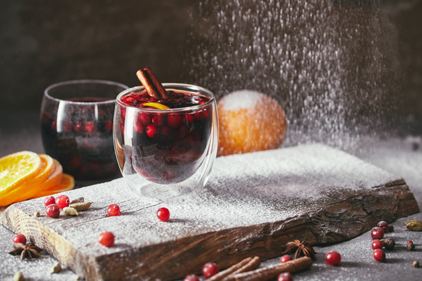 tasty homemade mulled wine with cranberries and falling powdered sugar in kitchen - Foto, Bild