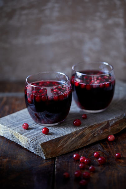 two glasses of homemade mulled wine with cranberries on wooden stand in kitchen - Foto, immagini