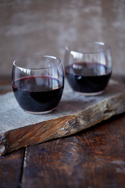 Deux verres de vin rouge fait maison sur pied en bois dans la cuisine
 - Photo, image
