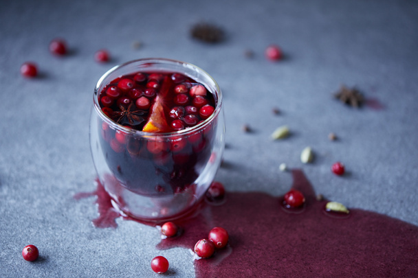 glass of homemade mulled wine with cranberries and orange on tabletop in kitchen - Photo, Image