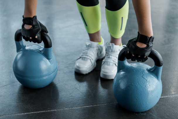 baixa seção de esportista em treinamento luvas de levantamento de peso com kettlebells no ginásio
 - Foto, Imagem