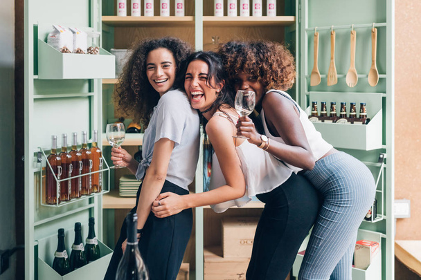 drei junge Frauen trinken nach Feierabend drinnen - Erfolg feiern, Feierabend, Entspannungskonzept - Foto, Bild