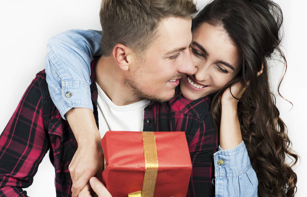 young couple in love guy and girl give each other a gift and react emotionally looking at the box - Fotó, kép