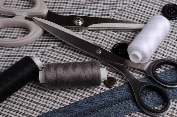 Nástroje a příslušenství pro šití. Šicí vlákno, nůžky, knoflíky, zip na šedé textilní pozadí. Detailní záběr - Fotografie, Obrázek