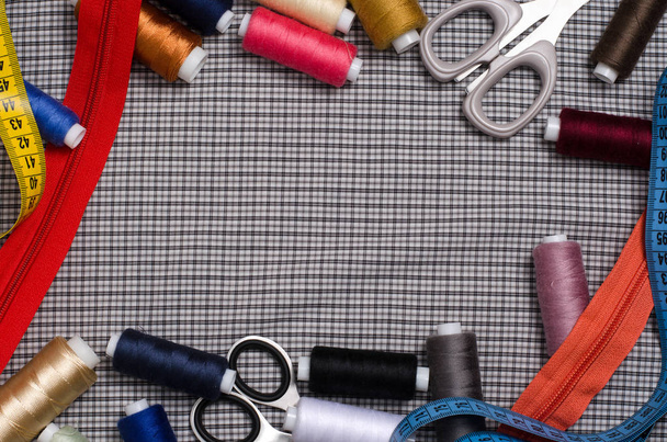 Tools and accessories for sewing. Sewing thread, scissors, zipper on gray textile background. Flat top view. Space for tex - Photo, Image