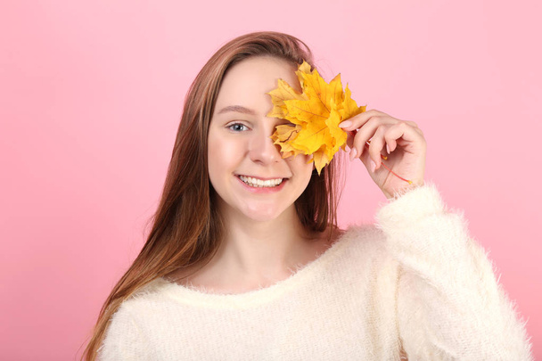 Young girl with dry leaves on pink background - Foto, imagen