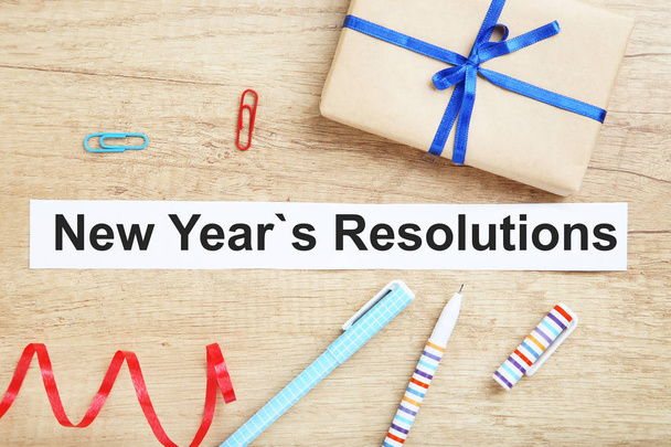 New year resolutions on sheet of paper with pens and gift box - Foto, afbeelding
