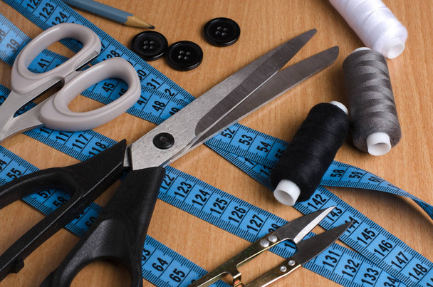 Tools and accessories for sewing. Sewing thread, scissors, tailor tape on a wooden table. Close up - Fotoğraf, Görsel
