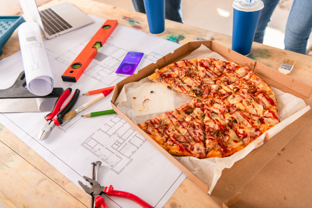 close-up shot of box with pizza, tools and smartphone with shopping app on screen on building plan - Photo, Image