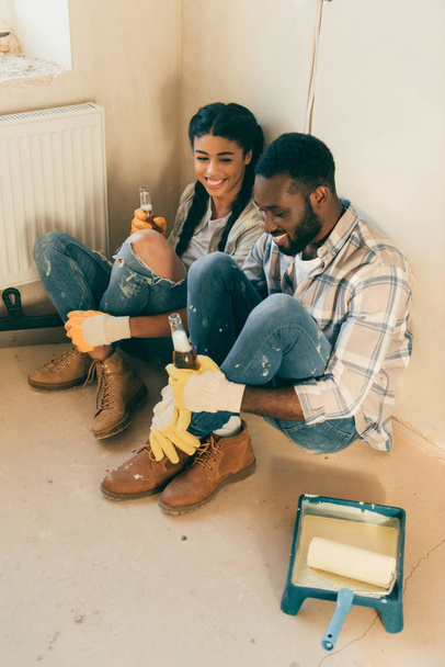high angle view of couple sitting on floor with beer while making renovation of home - Foto, afbeelding