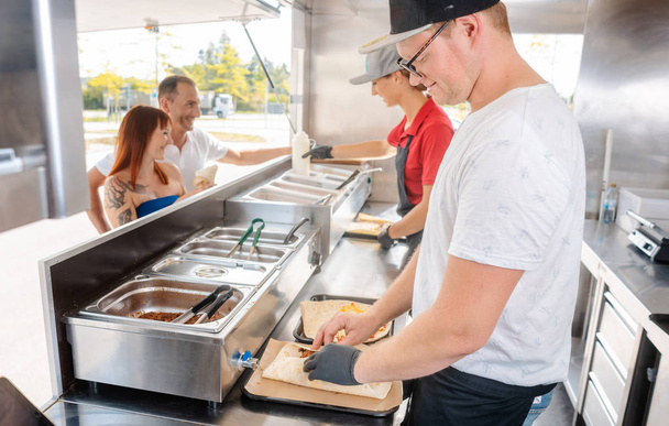 Jóvenes chefs en un camión de comida preparando comida
 - Foto, imagen