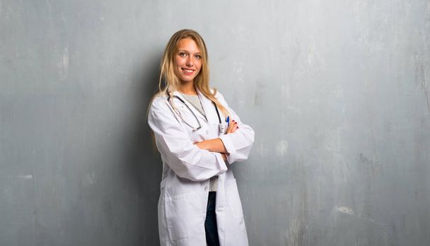 Young doctor woman keeping the arms crossed in lateral position while smiling - 写真・画像