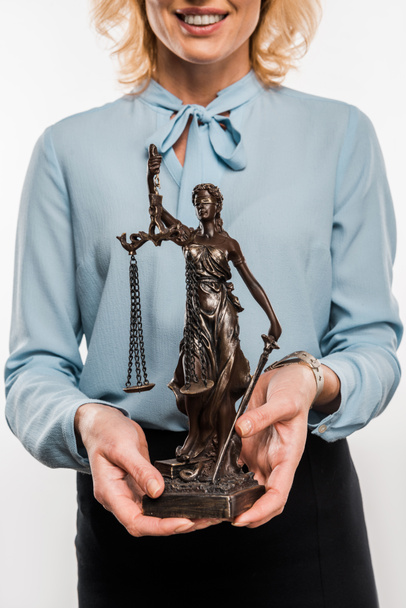 περικοπεί το πλάνο της χαμογελαστή γυναίκα δικηγόρος κρατώντας κυρία δικαιοσύνης άγαλμα απομονωθεί σε λευκό  - Φωτογραφία, εικόνα