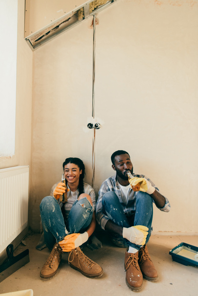 Afrika kökenli Amerikalı çift yenileme sırasında evde bira içme gülüyor - Fotoğraf, Görsel