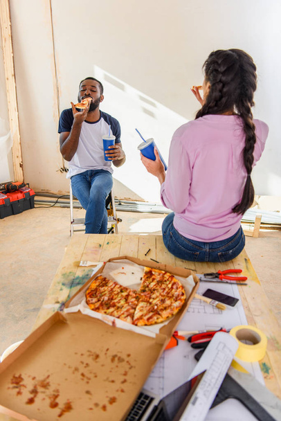 自宅の改修中にピザとソーダとランチを持っているアフリカ系アメリカ人のカップル - 写真・画像