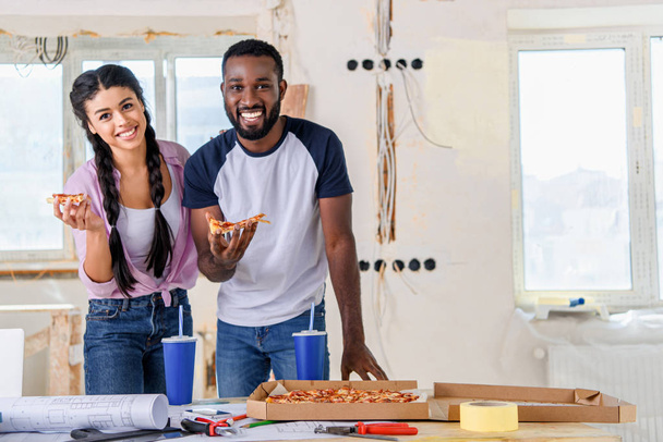heureux couple afro-américain déjeuner avec pizza et soda pendant la rénovation à la maison
 - Photo, image