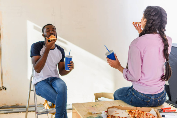 Młoda para african american obiad z pizza i soda podczas remontu  - Zdjęcie, obraz