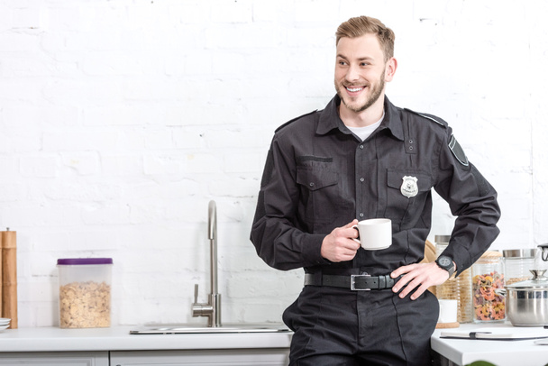 Handsome police officer drinking coffee at kitchen - Foto, Imagem