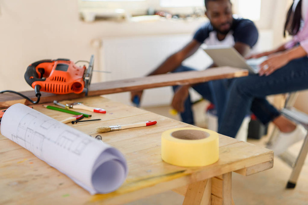 вибірковий фокус дерев'яного столу з відбитками і парою, що сидить позаду під час ремонту вдома
 - Фото, зображення