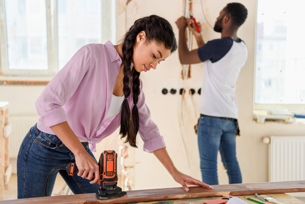 enfoque selectivo de la mujer afroamericana que trabaja con rompecabezas, mientras que su novio de pie detrás durante la renovación en casa
 - Foto, imagen
