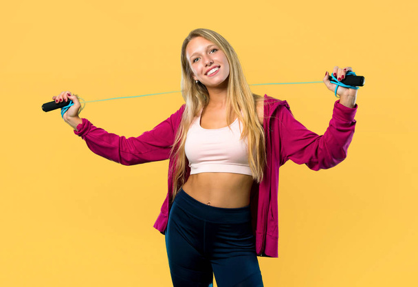 Pretty sport woman with jumping rope on yellow background - Foto, afbeelding
