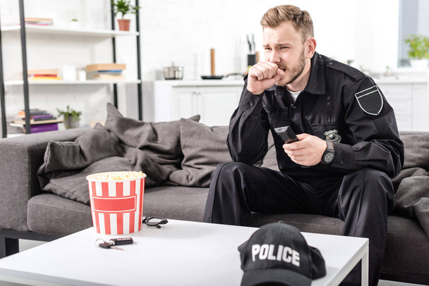 policeman with scared face expression sitting on couch and watching movie - Fotoğraf, Görsel