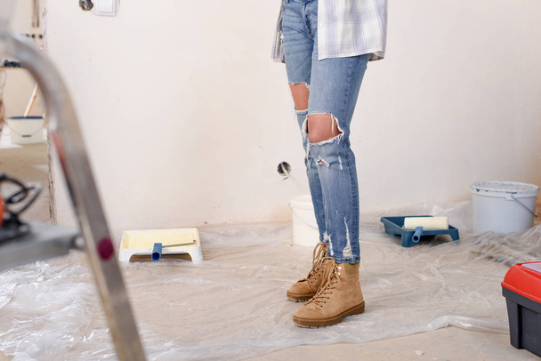 низька частина жінки в стильних джинсах, що стоять під час ремонту будинку
 - Фото, зображення
