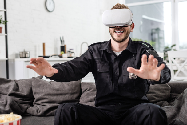 ビデオゲームのソファの上の頭の上の仮想現実ヘッドセットと警官 - 写真・画像